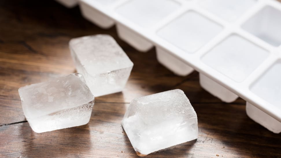 A few ice cubes sit next to a traditional ice cube tray.