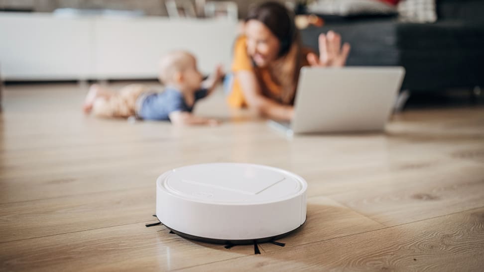 Robot vacuum cleaning the floor in front of a mother and child