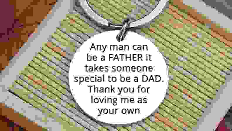 A silver, circular key chain that says "Any man can be a father it takes someone special to be a dad. Thank you for loving me as your own."