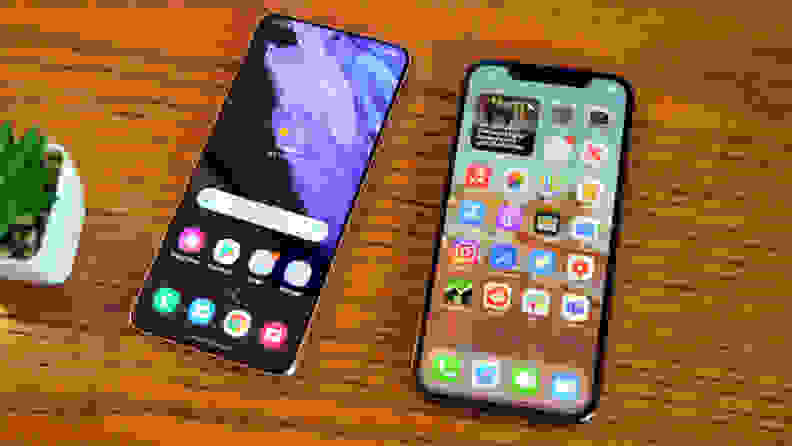 Two iPhones lying side by side on a brown table.