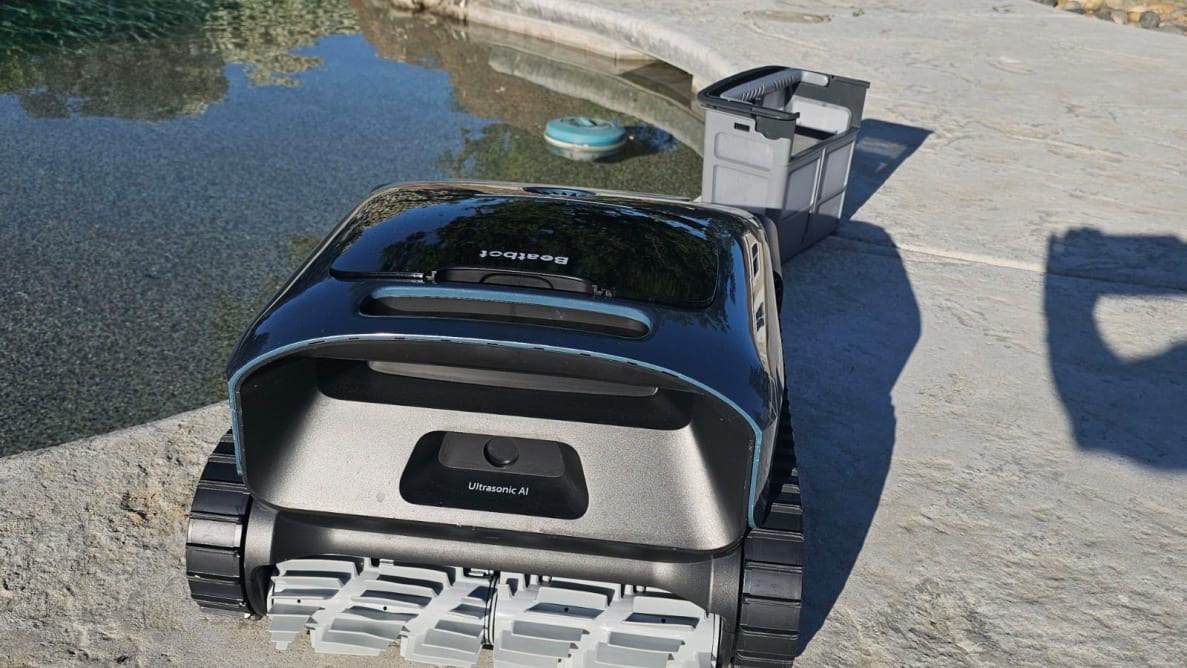 The Beatbot AquaSense Pro robot pool vacuum sitting beside a pool.