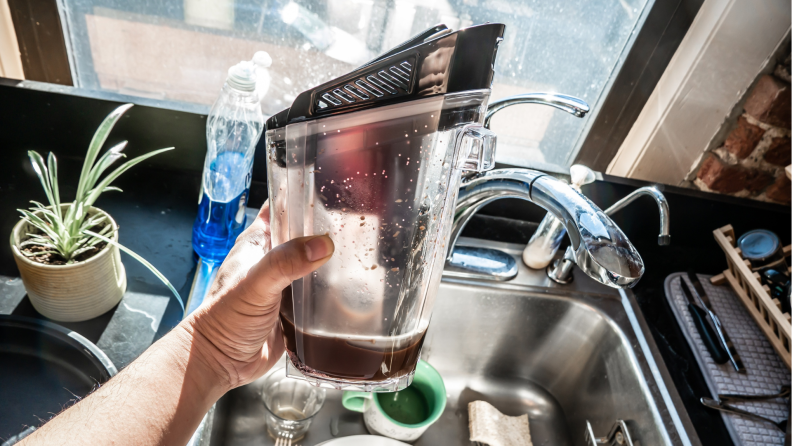 Person holding up water reservoir from the Bissell Crosswave Hydrosteam.