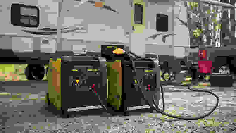 An inverter generator sitting on the ground outside an RV.
