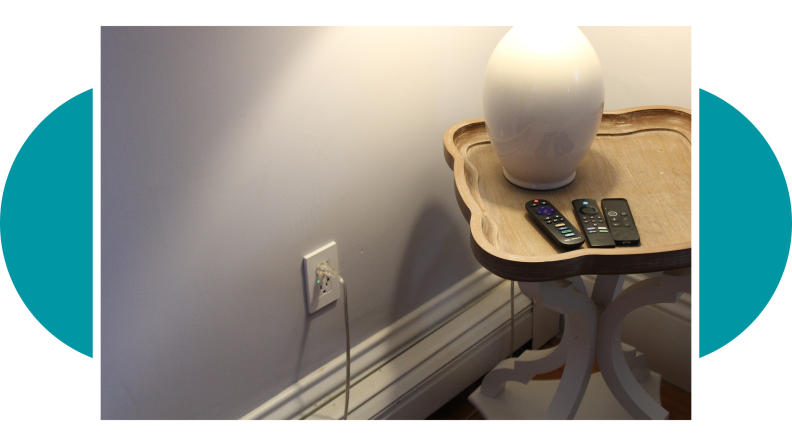 The corner of a room with the smart outlet fully installed with a lamp plugged in.