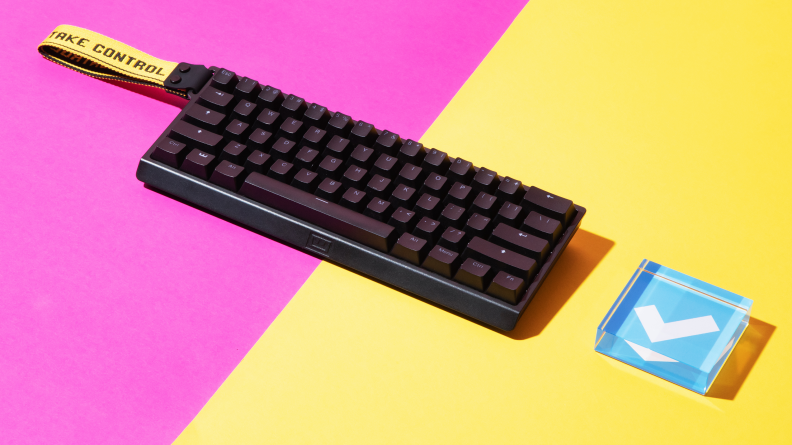 A 60 percent keyboard in black, the wooting 60he, on a yellow and pink background