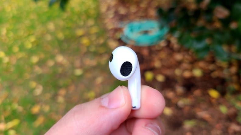 The all-white AirPod sits in a hand