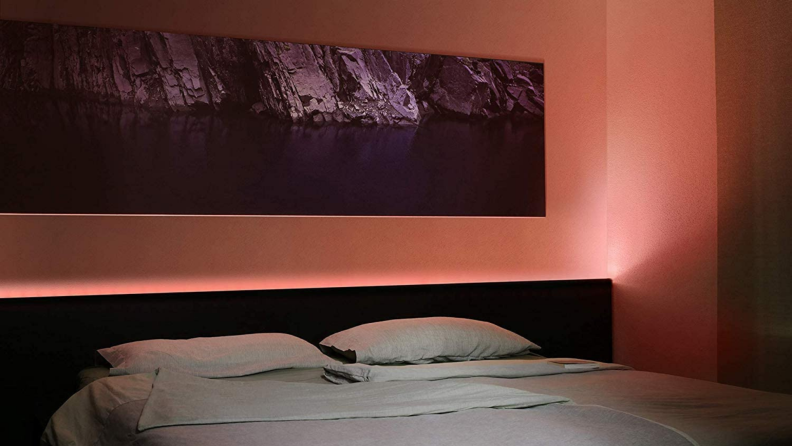 A light strip illuminates a bedroom in a shade of peach