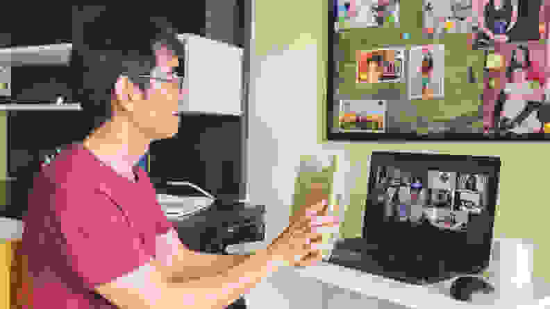 Man at home attending to a video conference with online book club members reading together.