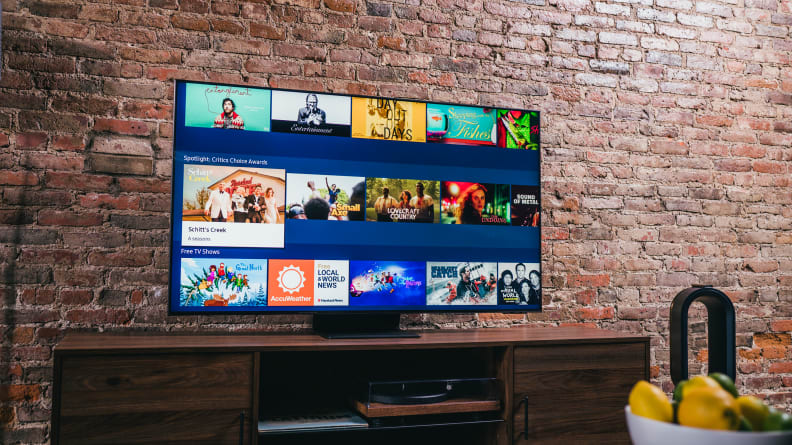 The Samsung QN90A displaying the home screen of its Tizen-based smart platform in a living room setting