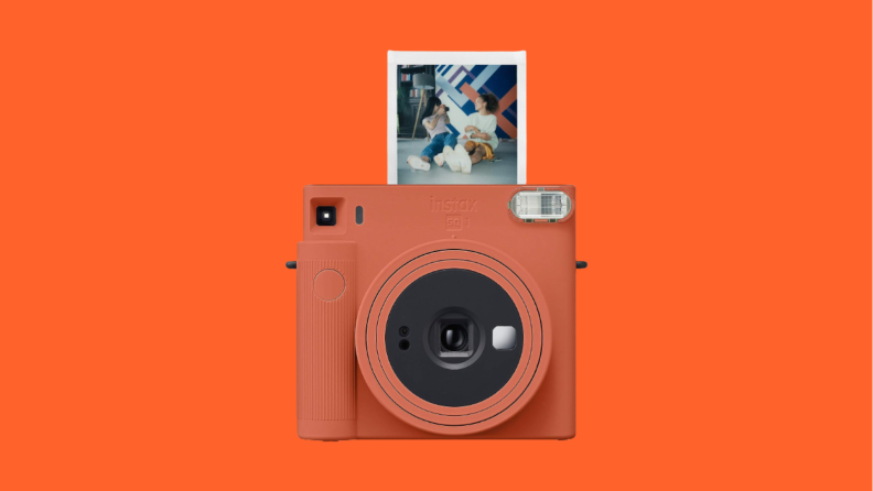 Orange camera with photograph against orange background