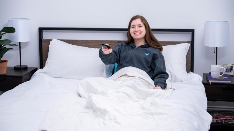 Woman in bed with a remote in her hand, presumably watching TV.