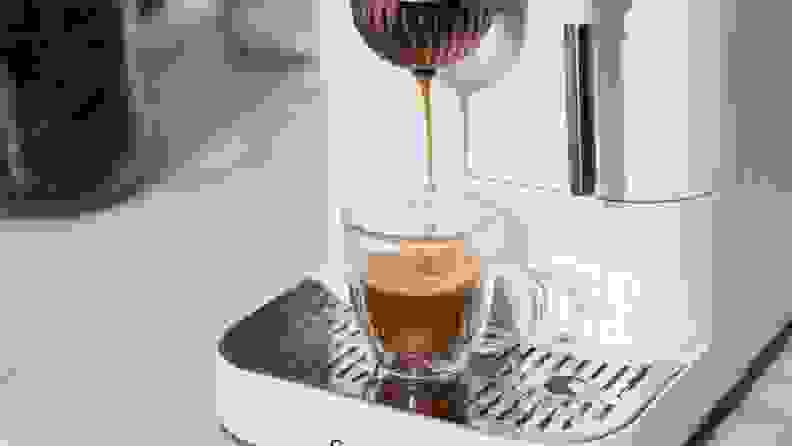Close-up of Affetto machine pouring crema-topped espresso into a glass shot mug.