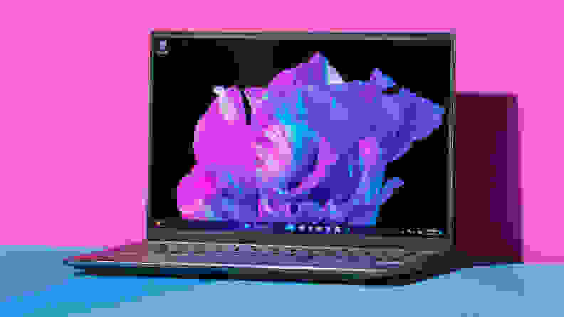 The Acer Swift X 14 laptop on a blue table with a pink background.