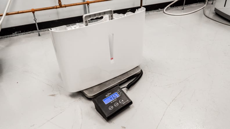 A dehumidifier reservoir sits on a scale to measure the weight of water.
