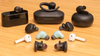 A bunch of different true wireless earbuds side by side on a table