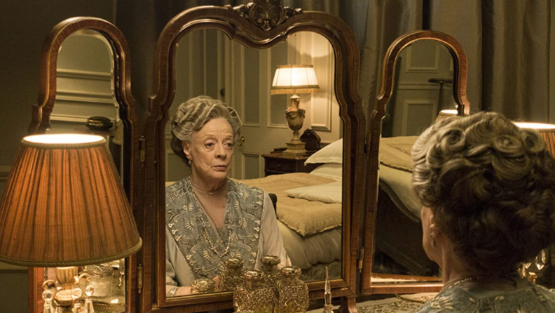 A still from Downton Abbey featuring Maggie Smith in front of a mirror.