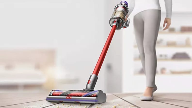 A person vacuums a home floor with a Dyson vacuum.