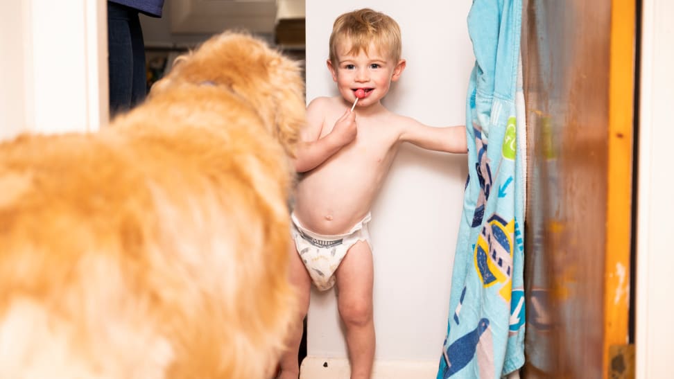 A little boy wearing a pair of Millie Moon diapers and sucking on a lollipop