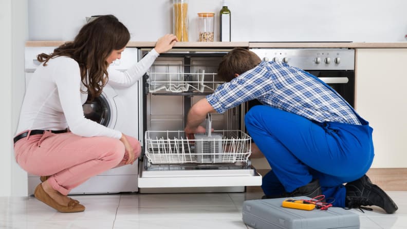 A homeowner and repairman inspects the dishwasher