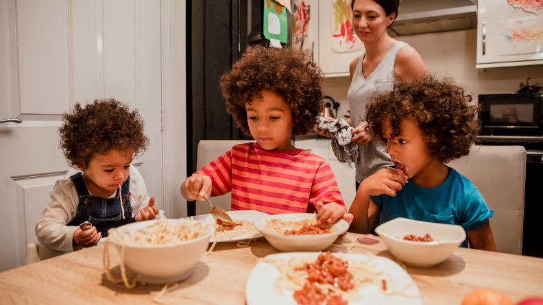 Three boys at dinner eating pasta