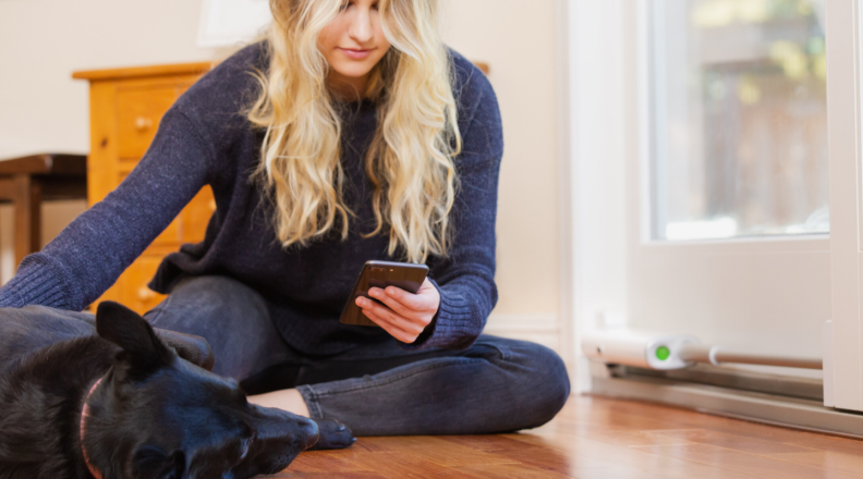 Woman on floor holding phone petting dog