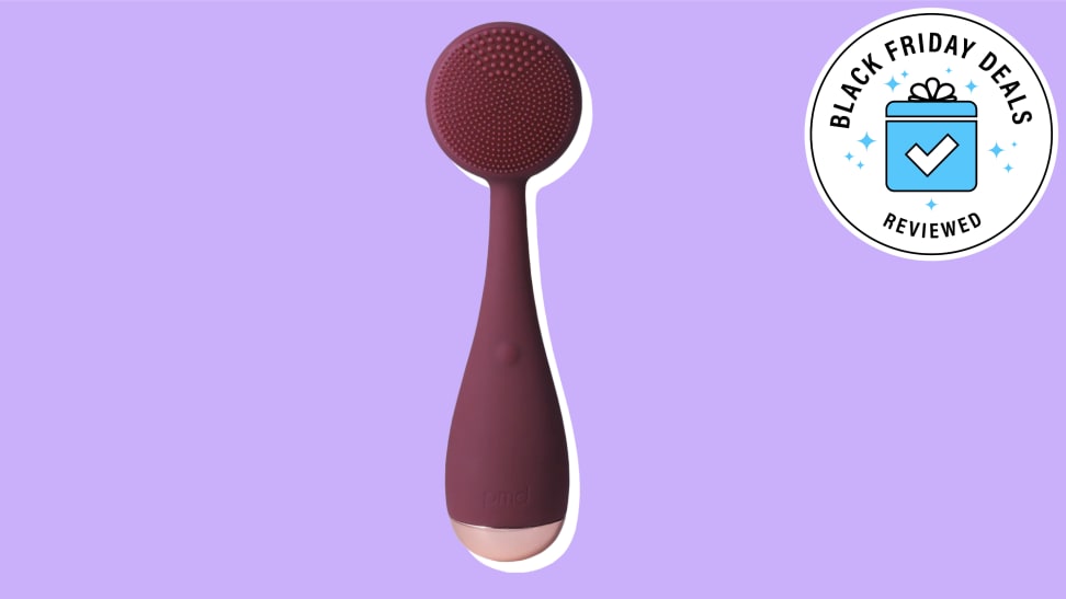 PMD Beauty cleansing brush against a purple background.