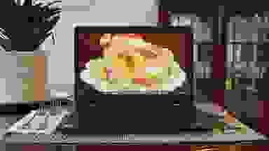 A laptop displaying a picture of a cooked turkey, on a dinner table