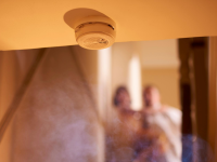 Smoke detector with smoke and a family in the background