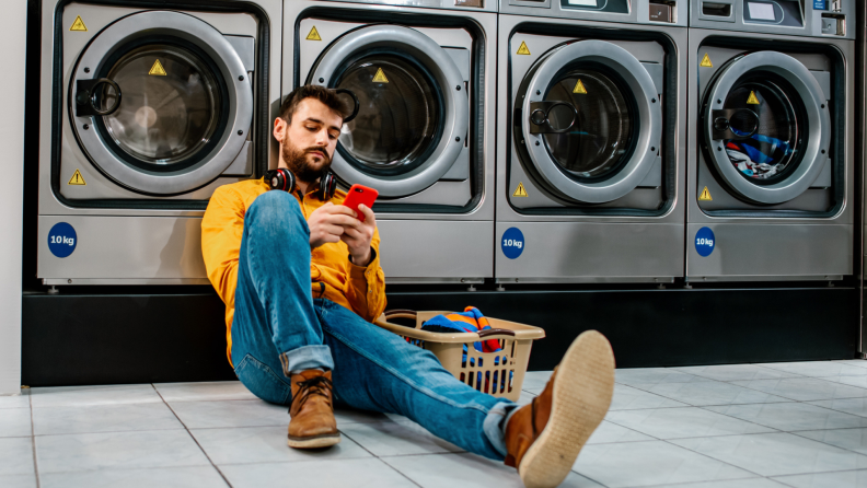 A person sets a timer on their cell phone while waiting for laundry in a laundromat.