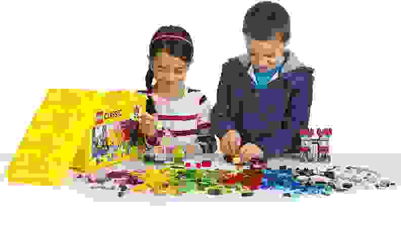 Two children playing with Lego blocks together at table.