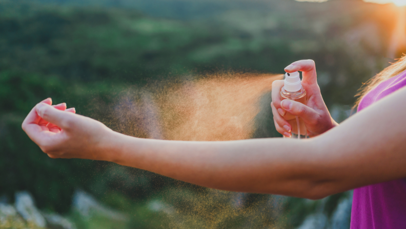 A person sprays their arm with bug spray.