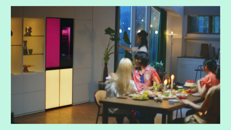 Group of friends sitting in kitchen at table while admiring the LG MoodUP refrigerator.