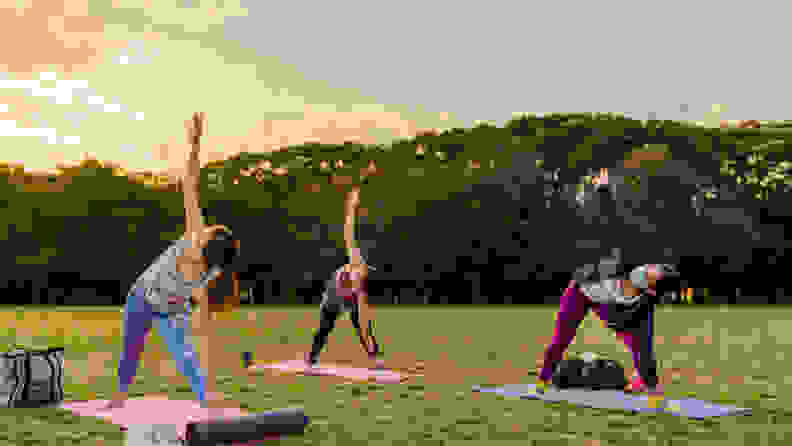 Three women performing yoga in a park.