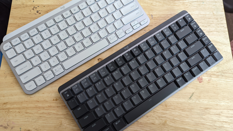 A white and a black keyboard in a wood surface.
