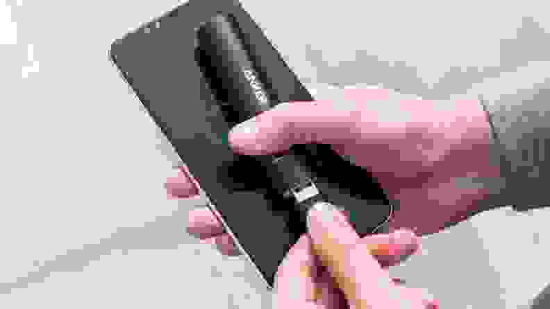 A person charges their smartphone using an Anker portable battery pack.