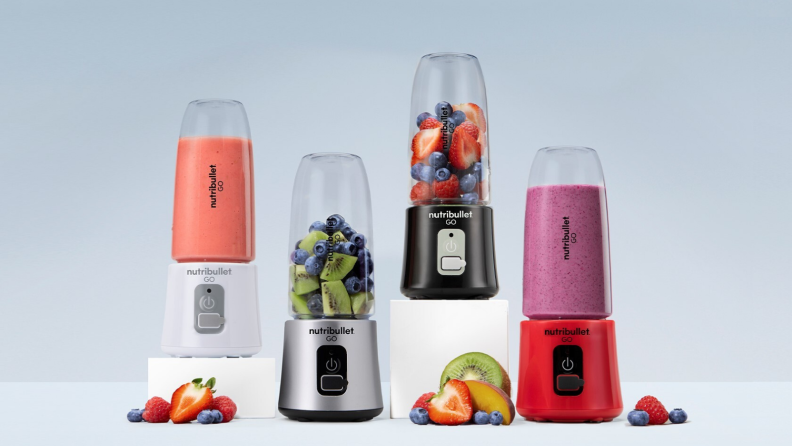 Four different NutriBullet Go blenders are on display, each with a different combination of fruit inside (or next to it): blueberries, strawberries, kiwi, and so on.