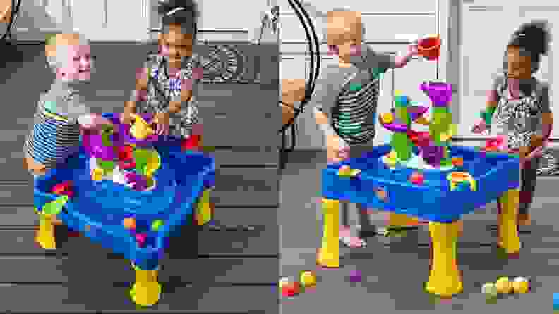 Two small children play with a water table