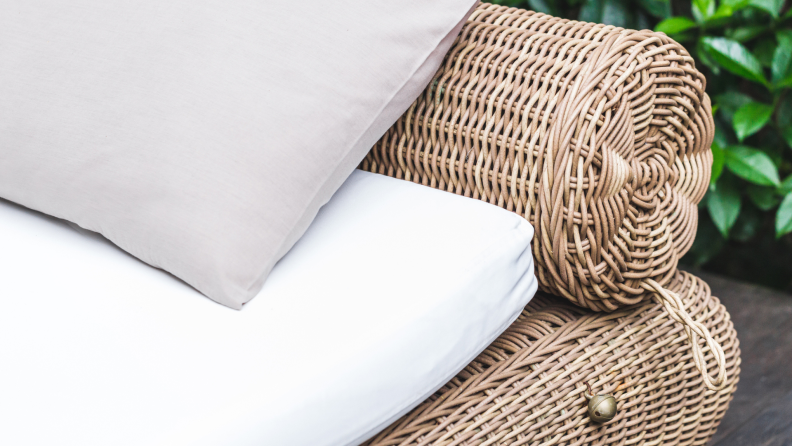Wicker daybed with white cushions outdoors.