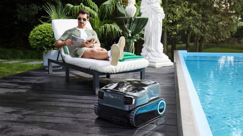 Man reads a magazine in a lounge chair to the left of the pool where the Aiper Scuba X1 Pro Max is