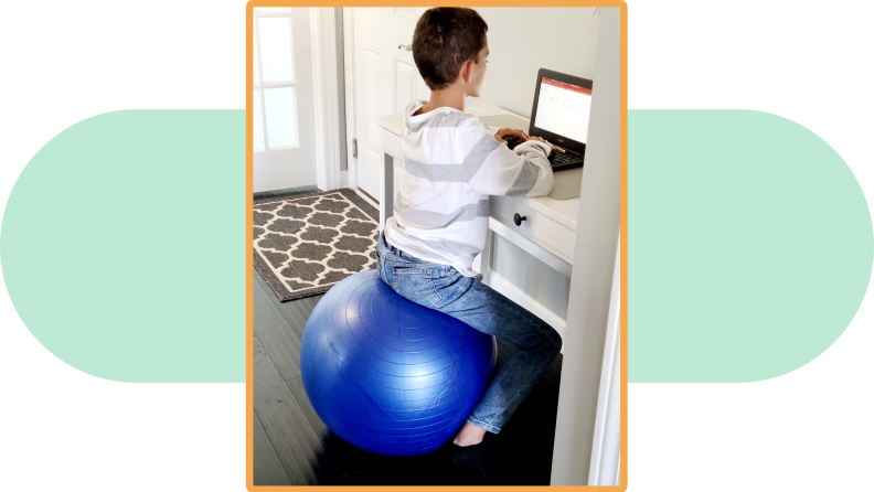A child sits on a URNBN Exercise Ball while on a laptop.
