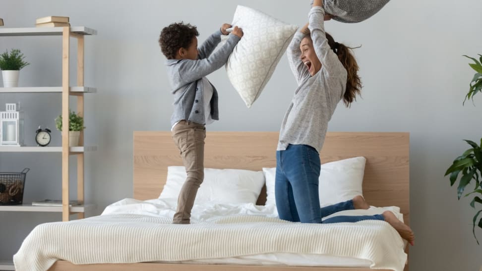 a parent and child have a pillow fight on a mattress