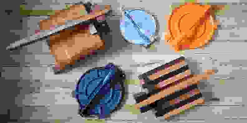 Five tortilla presses laid out on a wooden backdrop, shot from above.