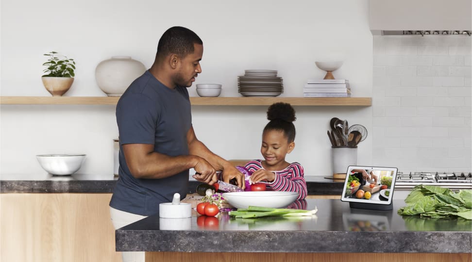 A dad and daughter use the Google Nest Hub Max, one of Google's smart display screens, to cook in the kitchen.