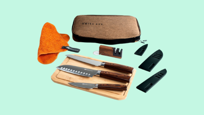 Knife set laid out, including cloth, case, knife sharpener, 3 knife covers and 3 knives sitting on a cutting board.