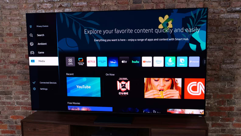 The Samsung S95C QD-OLED TV on an entertainment center next to a brick wall.