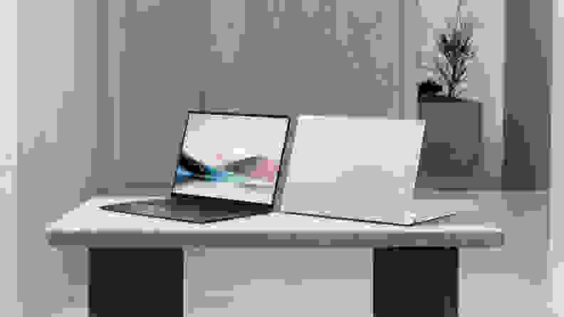 Two Asus Zenbook S 16 laptops, one with its screen facing the camera and one facing away, sitting on a table in a modern-styled room.