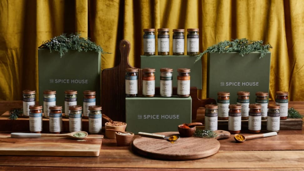 Four Spice House boxes and dozens of spice jars laid out on a wooden countertop.