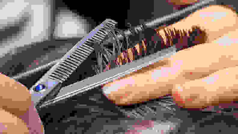 A photo of a man using thinning shears on his hair.