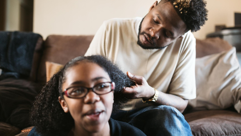 Father braiding daughter's hair