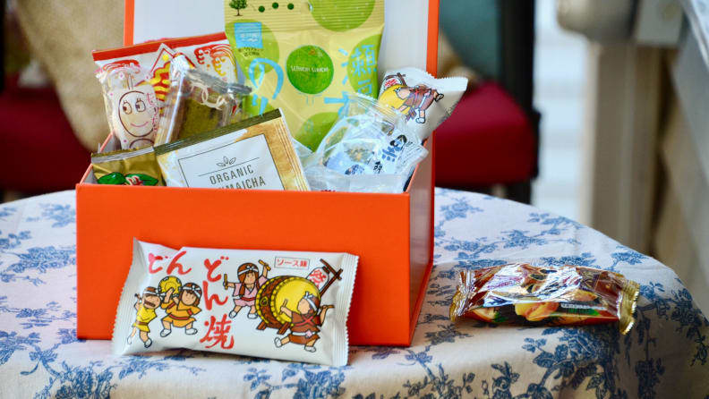 A box of Bokksu Japanese snack subscription box is opened up. Inside the box, there's an assortment of individually-packaged sweet and savory treats.